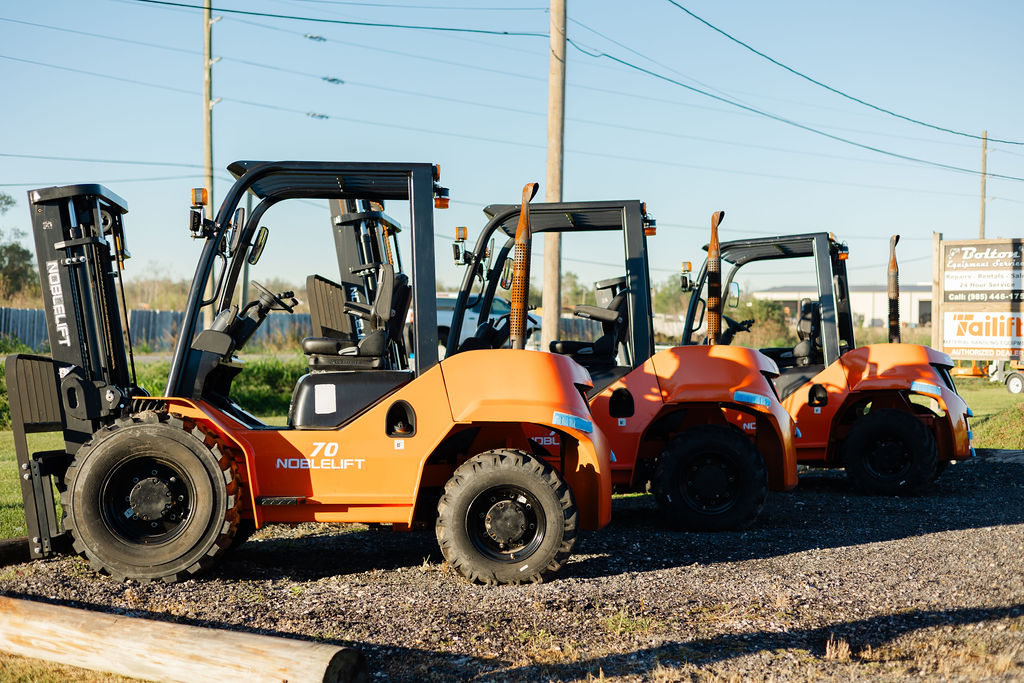 Lineup of Noblelift rough-terrain forklifts in front of the Bolton Equipment sign