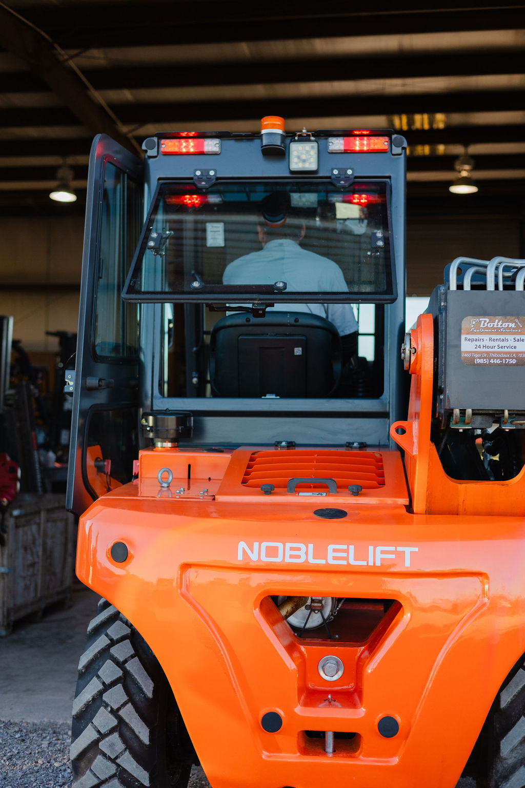 Rear view of a Noblelift rough-terrain forklift with a Bolton Equipment placard