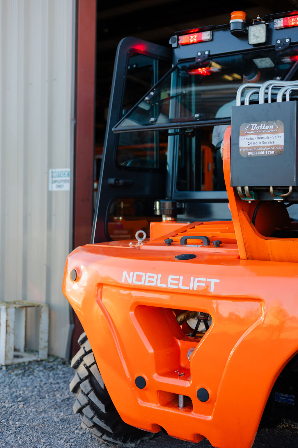 Close-up of a Noblelift rough-terrain forklift with a Bolton Equipment Services placard at the Thibodaux shop